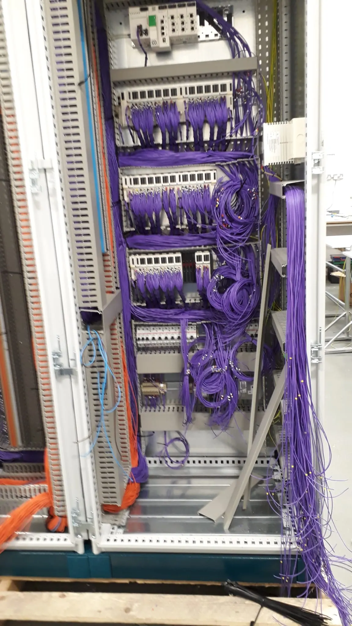 Control cabinet with purple wiring bundled and looped to rows of I/O modules