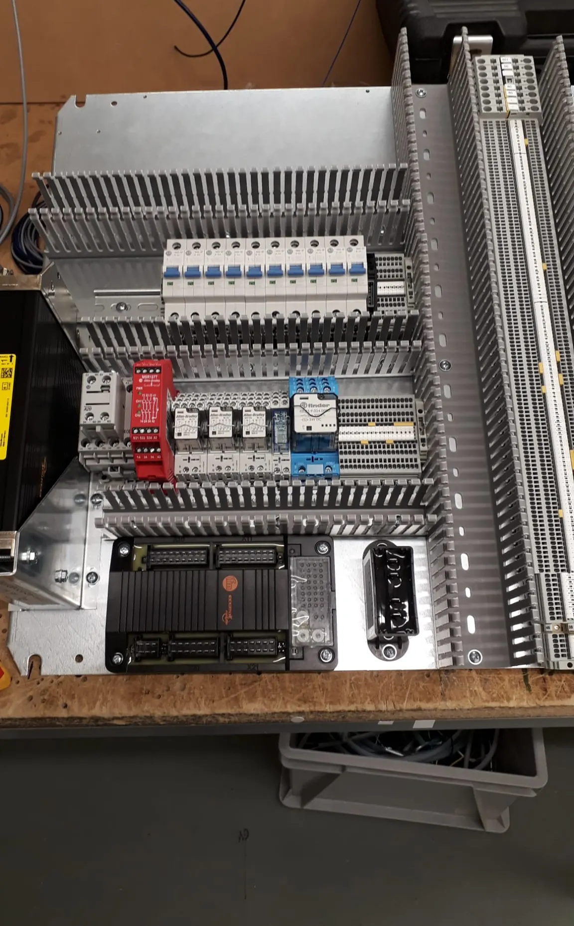 Control panel components mounted on a plate with trunking, breakers, relays and terminals on a workbench